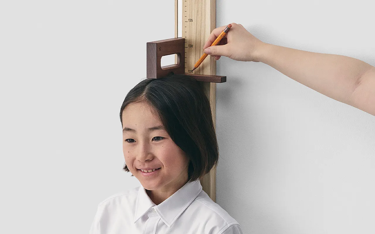 木製の身長計 子どもの身長を測って鉛筆で記録する様子
